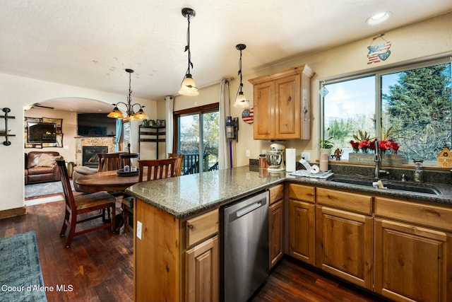 kitchen with decorative light fixtures, stainless steel dishwasher, kitchen peninsula, and sink