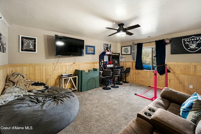 carpeted living room with ceiling fan and wooden walls