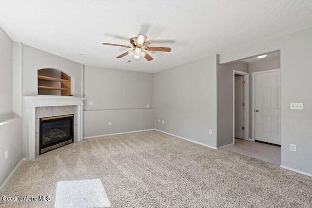 unfurnished living room featuring a textured ceiling, ceiling fan, light colored carpet, and a tile fireplace