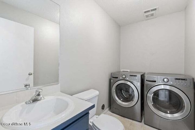 bathroom featuring toilet, vanity, independent washer and dryer, and a textured ceiling