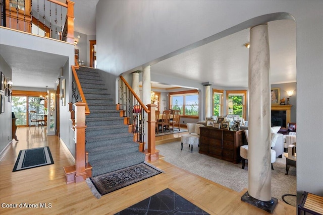 entryway featuring wood-type flooring, ornate columns, and a notable chandelier