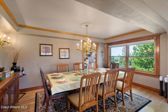 dining space with a raised ceiling, light wood-type flooring, and an inviting chandelier