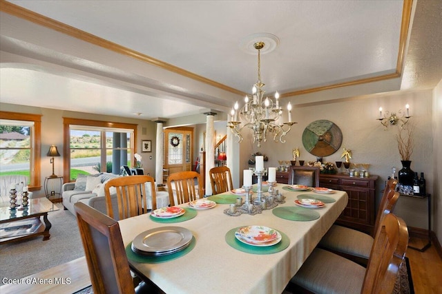 dining room featuring hardwood / wood-style floors, decorative columns, a tray ceiling, a chandelier, and crown molding