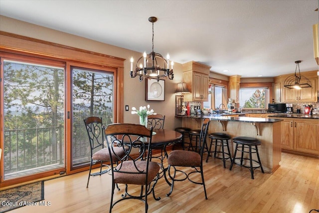 dining space with light wood-type flooring, an inviting chandelier, and sink