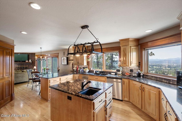 kitchen featuring decorative light fixtures, dishwasher, sink, and a kitchen island