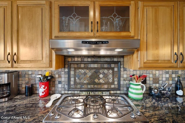 kitchen with stove, decorative backsplash, dark stone counters, and extractor fan