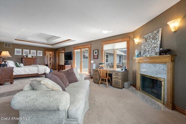 carpeted bedroom with a raised ceiling and a fireplace