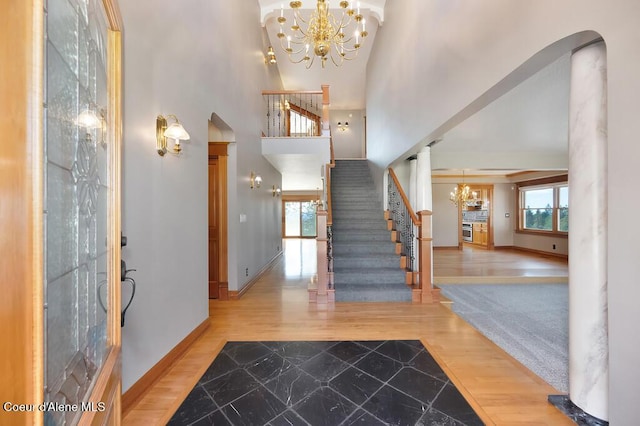 entryway featuring plenty of natural light, baseboards, a towering ceiling, and an inviting chandelier