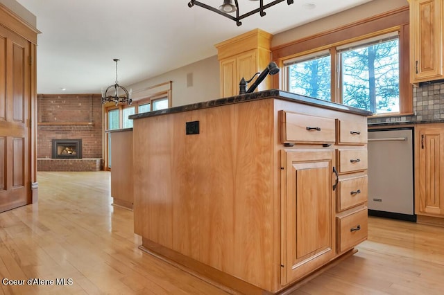 kitchen featuring decorative backsplash, light brown cabinetry, light wood-style flooring, a chandelier, and a fireplace