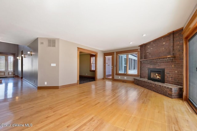 unfurnished living room with baseboards, visible vents, light wood finished floors, and a fireplace