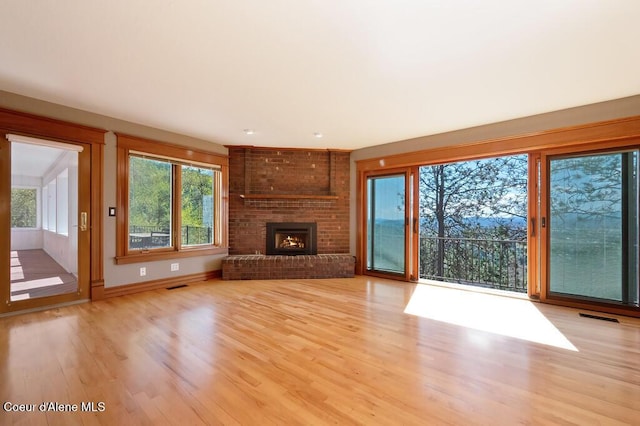 unfurnished living room with wood finished floors, visible vents, and a fireplace