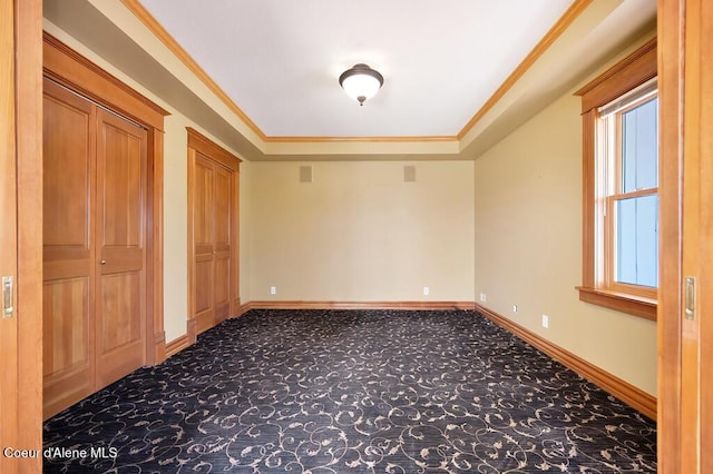 unfurnished bedroom with baseboards, carpet floors, crown molding, and two closets