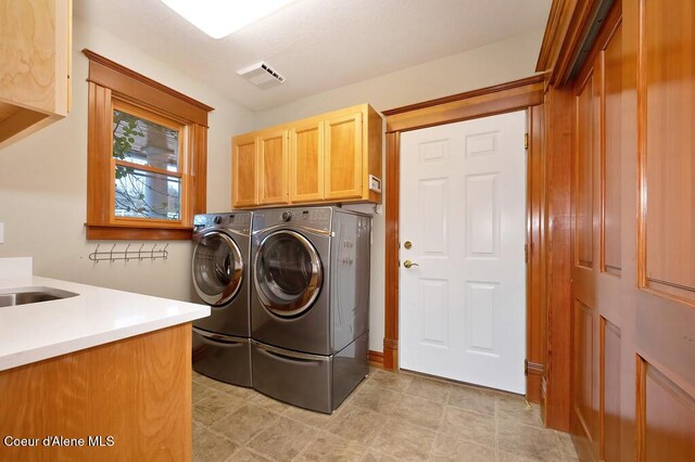 laundry area featuring cabinet space, visible vents, washer and dryer, and a sink