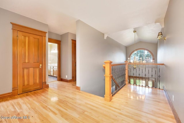 hall with wood finished floors, baseboards, and an upstairs landing