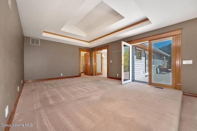 spare room featuring a raised ceiling, visible vents, and light carpet
