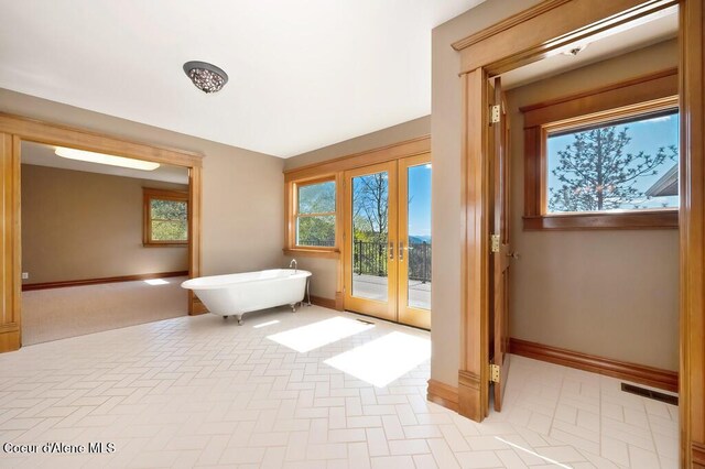 bathroom with a freestanding bath, baseboards, french doors, and visible vents