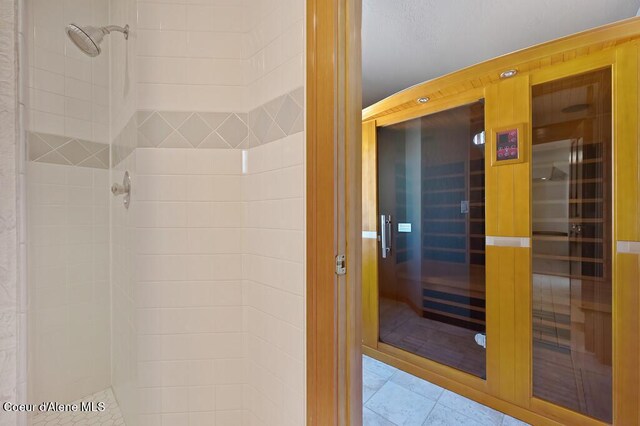 bathroom with a sauna, tile patterned floors, and tiled shower