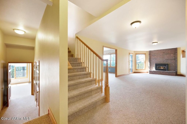 stairway featuring a high ceiling, a fireplace, baseboards, and carpet floors