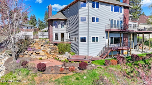 back of property with fence, a chimney, stairway, and a deck