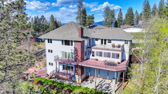 back of property with a chimney, a patio area, and a balcony