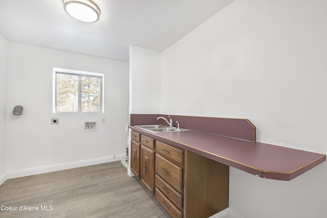 interior space with light wood-type flooring, a kitchen breakfast bar, kitchen peninsula, and sink