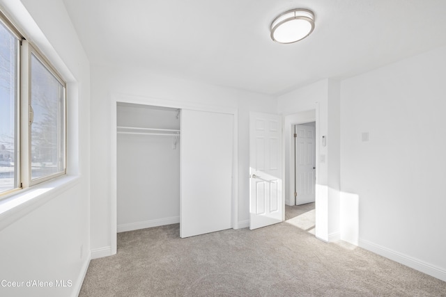 unfurnished bedroom with a closet and light colored carpet