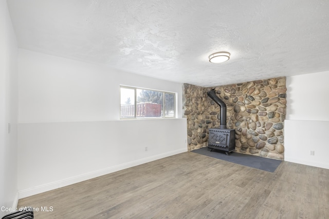 unfurnished living room featuring hardwood / wood-style floors, a wood stove, and a textured ceiling