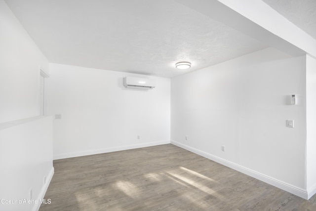 empty room with a textured ceiling, hardwood / wood-style floors, and a wall mounted air conditioner