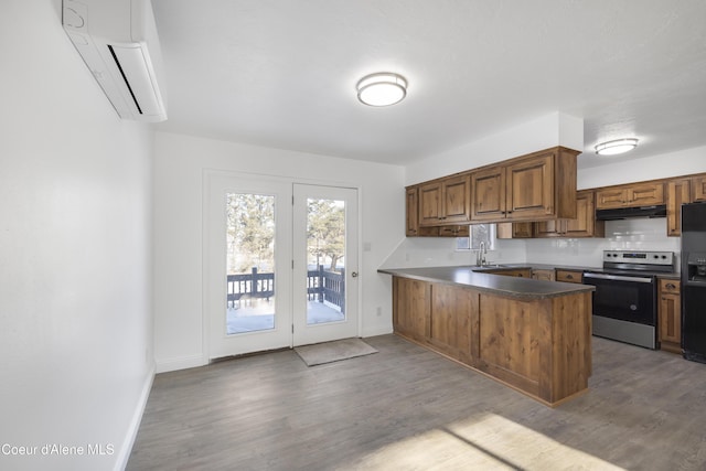 kitchen with stainless steel electric stove, sink, black fridge, kitchen peninsula, and a wall mounted air conditioner