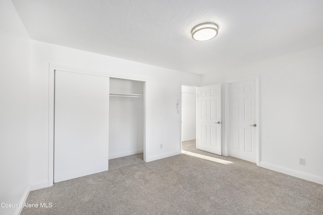 unfurnished bedroom with light carpet and a closet