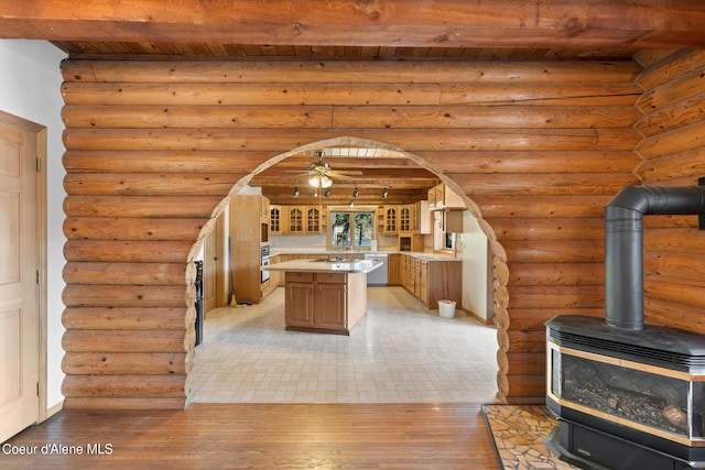 interior space with dishwasher, rustic walls, a center island, a wood stove, and wooden ceiling