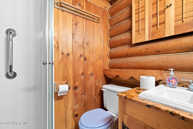 bathroom with wood walls, vanity, and toilet