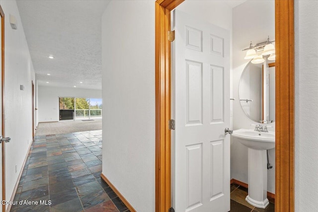 corridor featuring sink and a textured ceiling