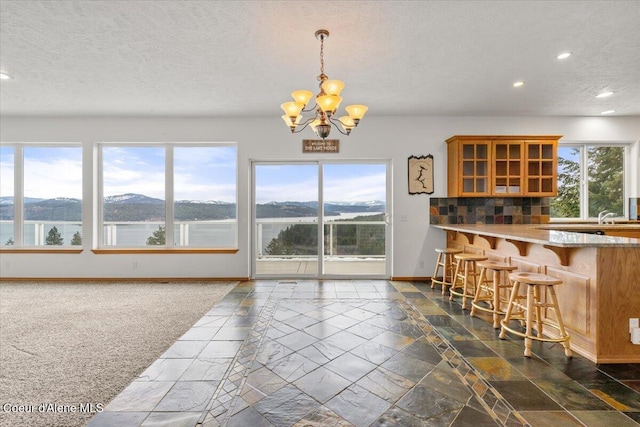 kitchen with a water and mountain view, hanging light fixtures, tasteful backsplash, a chandelier, and a breakfast bar area