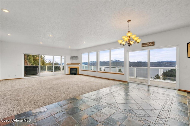 unfurnished living room with a textured ceiling, a chandelier, a water view, and carpet floors