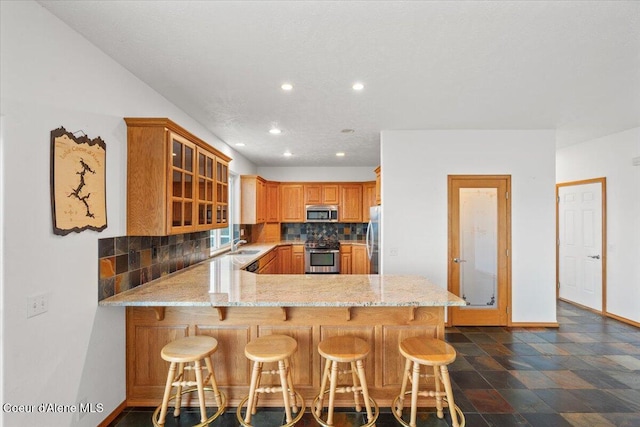 kitchen with kitchen peninsula, stainless steel appliances, a breakfast bar area, and tasteful backsplash