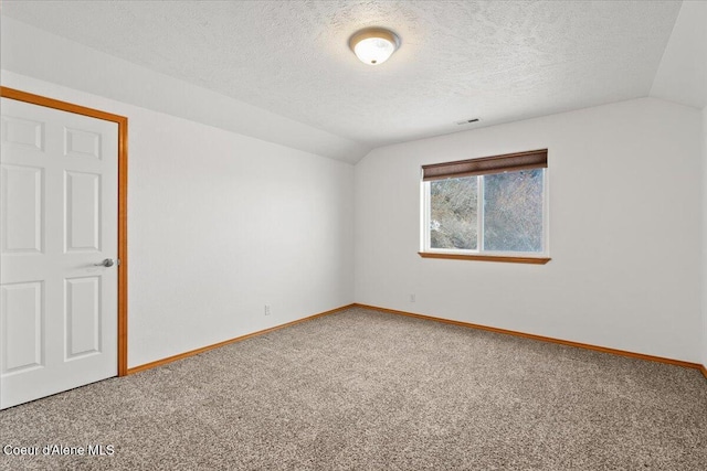 spare room with carpet flooring, a textured ceiling, and lofted ceiling