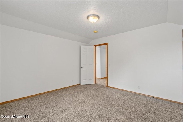 carpeted spare room featuring a textured ceiling and vaulted ceiling