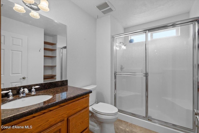 bathroom with a textured ceiling, toilet, walk in shower, and vanity