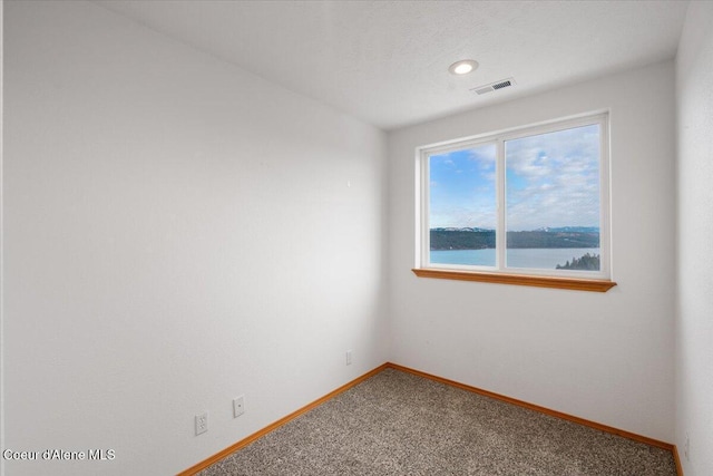 unfurnished room featuring a water view and carpet floors