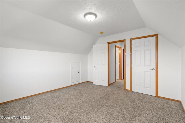 additional living space with carpet, a textured ceiling, and vaulted ceiling