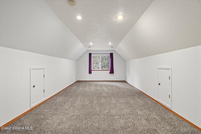 bonus room featuring vaulted ceiling, carpet flooring, and a textured ceiling