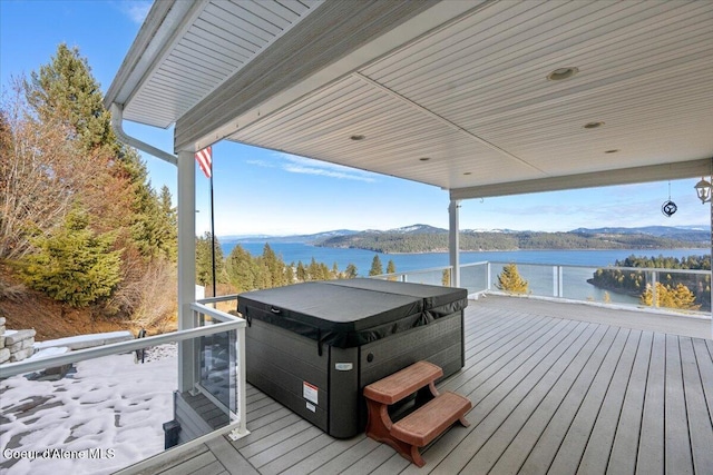 wooden deck with a water and mountain view and a hot tub