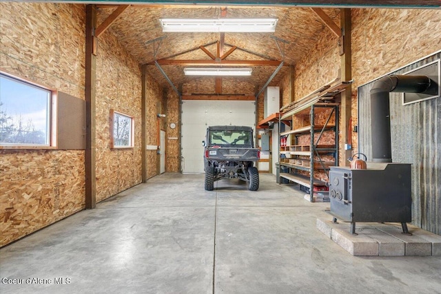 interior space with concrete floors, beam ceiling, high vaulted ceiling, and a wood stove