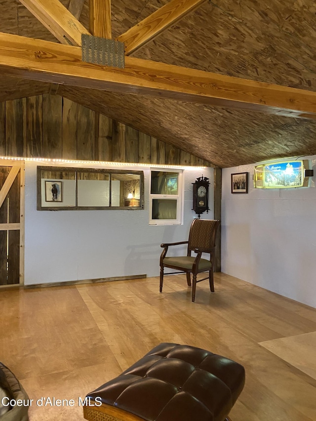 living area featuring wood-type flooring, wooden walls, and vaulted ceiling with beams