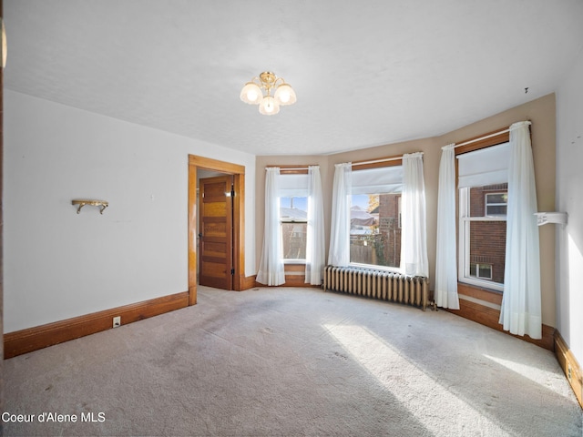 carpeted empty room with an inviting chandelier and radiator