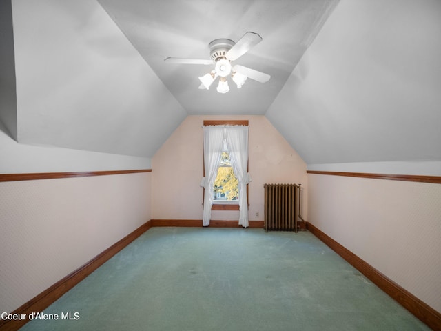 additional living space with radiator heating unit, ceiling fan, vaulted ceiling, and light colored carpet