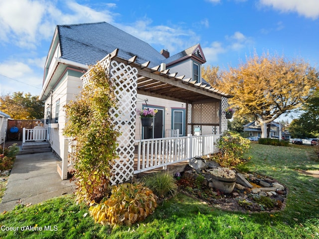 view of side of property featuring a pergola and a yard