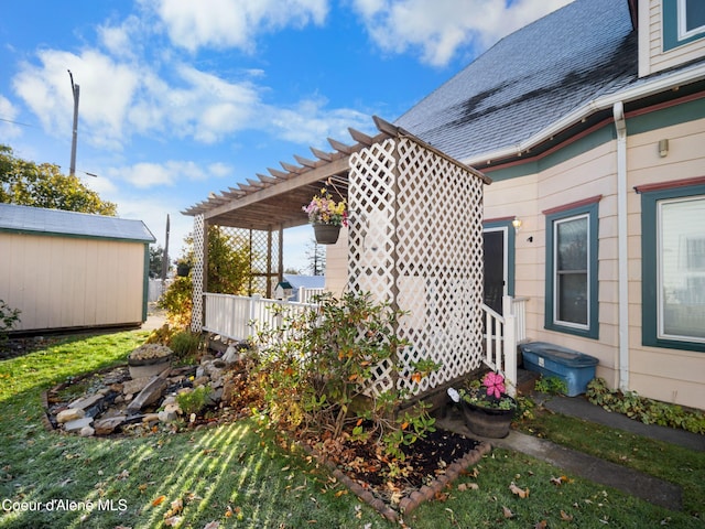 view of side of home featuring a lawn, a storage unit, and a pergola