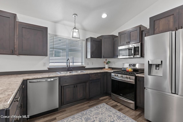 kitchen featuring dark wood-type flooring, sink, decorative light fixtures, vaulted ceiling, and appliances with stainless steel finishes